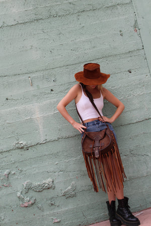 Model wearing brown suede fringe bag and suede bolero hat